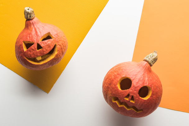 top view of Halloween pumpkins on white and orange background - Foto, Imagem