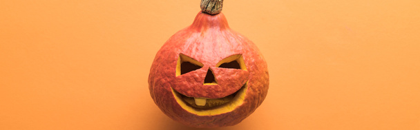 Panoramaaufnahme eines gruseligen Halloween-Kürbisses auf orangefarbenem Hintergrund - Foto, Bild