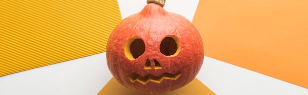 panoramic shot of spooky Halloween pumpkin on white and orange background - Photo, image