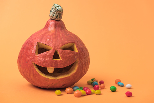 carved Halloween pumpkin with sweets on orange background - Foto, Bild