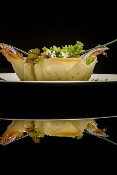 フェタチーズ、トマト、キュウリ、玉ねぎ、オリーブのクラシックなギリシャサラダ。絶妙な料理。クリエイティブなレストランの食事コンセプト。反射と黒のオートクチュール食品。ファインダイニングコンセプト. - 写真・画像