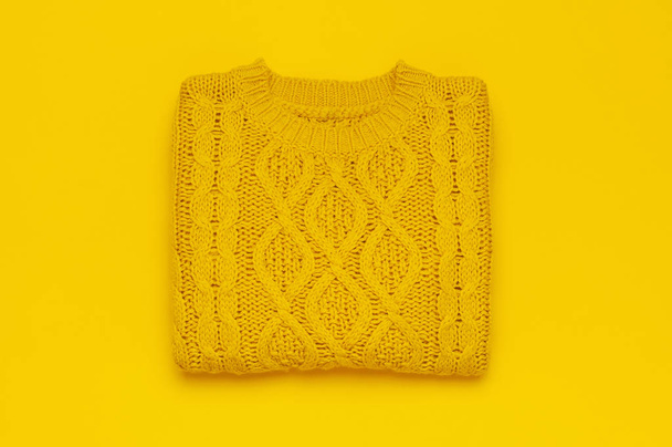 Autumn flat lay composition. Orange yellow knitted woolen female sweater on yellow background top view copy space. Fashionable women's fall winter accessories. Cozy Knit Jumper Stylish Lady Clothes - Фото, изображение