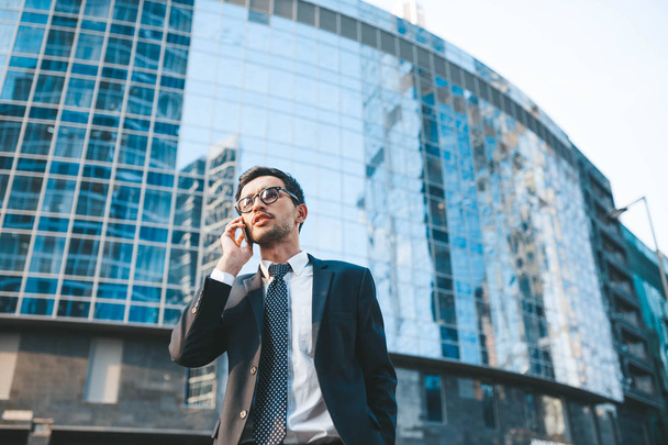 Modern businessman in full suit standing outdoors with cityscape in the background - Fotoğraf, Görsel