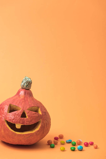 spooky Halloween pumpkin with candies on orange background - Foto, afbeelding