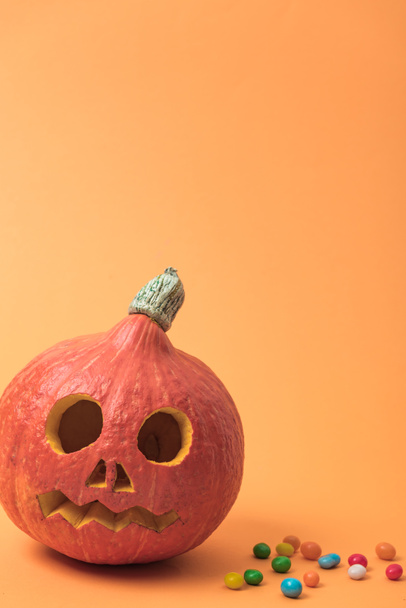 Halloween pumpkin with candies on orange background - Фото, зображення