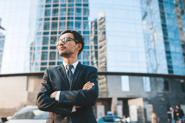 Modern businessman in full suit standing outdoors with cityscape in the background - 写真・画像