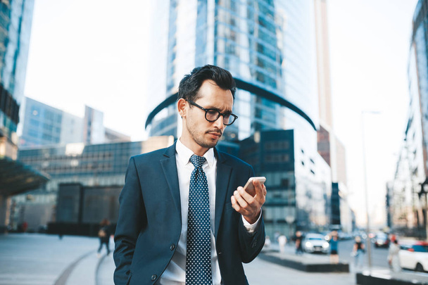 Modern businessman in full suit standing outdoors with cityscape in the background - Foto, Imagem