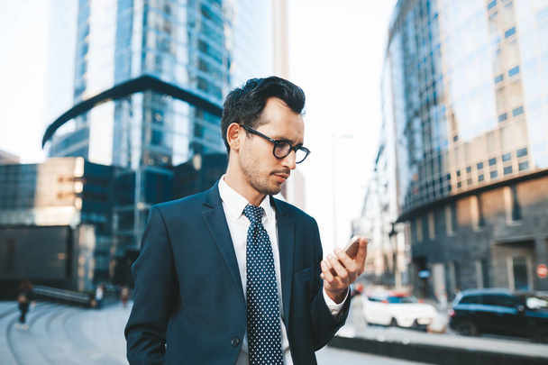 Modern businessman in full suit standing outdoors with cityscape in the background - Foto, Imagen