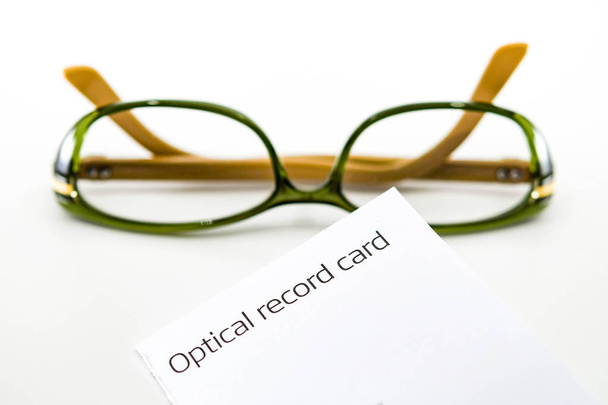 Cartão de registro óptico com um par de óculos femininos borrados no fundo isolados contra um fundo branco liso
 - Foto, Imagem