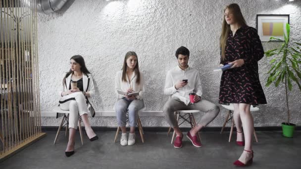 Різноманітні кандидати на вакансію, що сидять на стільцях, чекають своєї черги
 - Кадри, відео