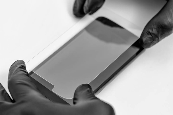 A man is holding a protective glass of a smartphone. - Photo, Image