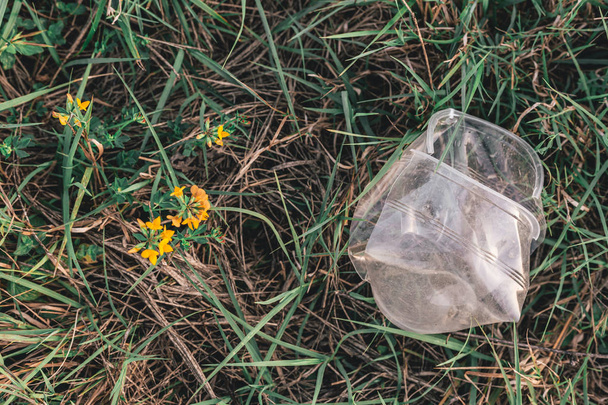 Empty transparent plastic cup in the grass. Pollution, ecological issues - Fotoğraf, Görsel