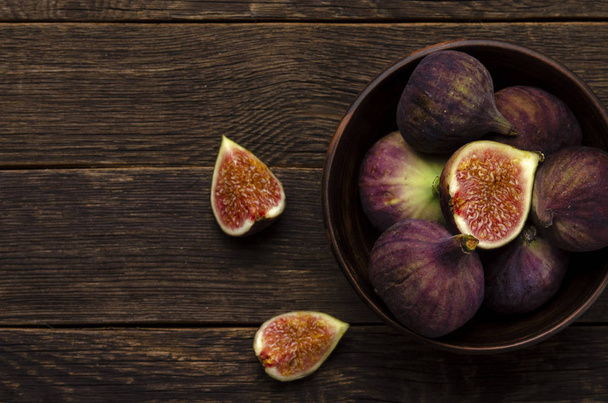 figs in a rustic ceramic bowl on the dark wooden background - Photo, image