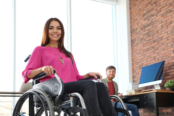 Young woman in wheelchair with colleague at office - Valokuva, kuva