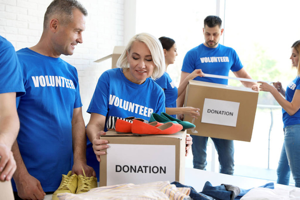 Team of volunteers collecting donations in boxes indoors - Foto, imagen