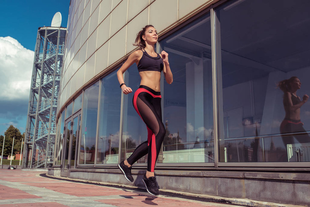 Sports beautiful girl in summer runs jogging, sportswear top leggings, morning bright sunny day. Active lifestyle, fitness motivation workout. In movement, a woman is strong and hardy. - Zdjęcie, obraz