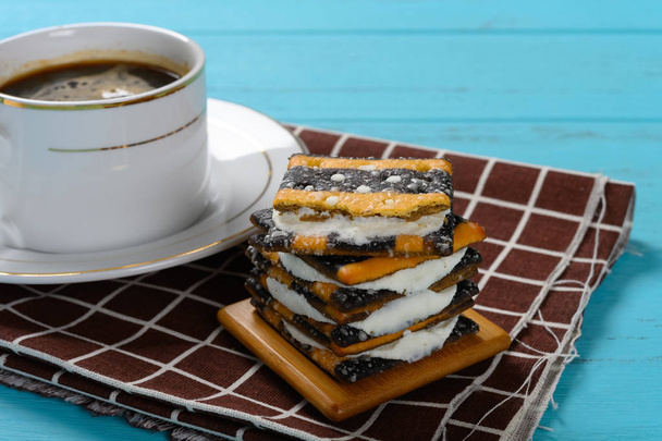 taza de café vista lateral y pila de galletas sándwich con relleno de crema blanca
 - Foto, Imagen