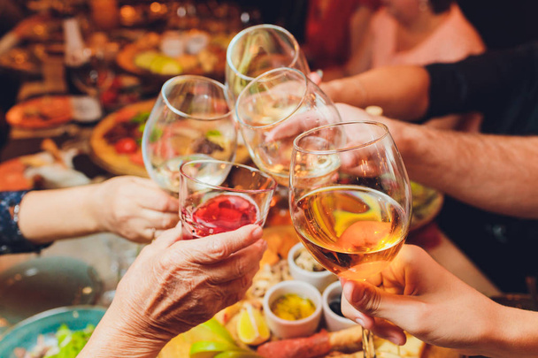 Close up shot of group of people clinking glasses with wine or champagne in front of bokeh background. older people hands - Foto, immagini
