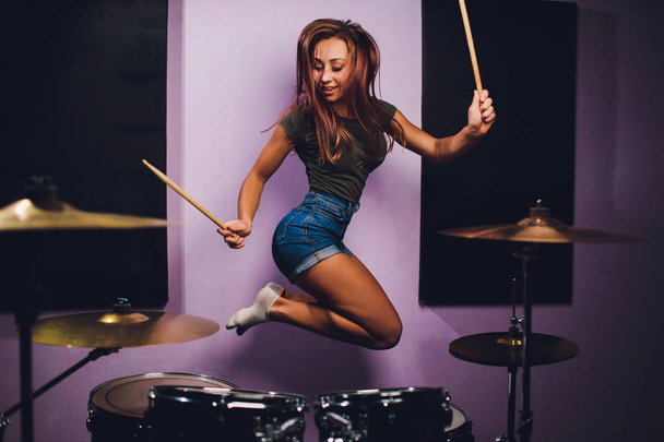 Photograph of a female drummer playing a drum set on stage. - Foto, Imagen