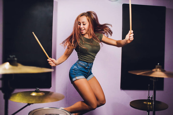 Photograph of a female drummer playing a drum set on stage. - Valokuva, kuva