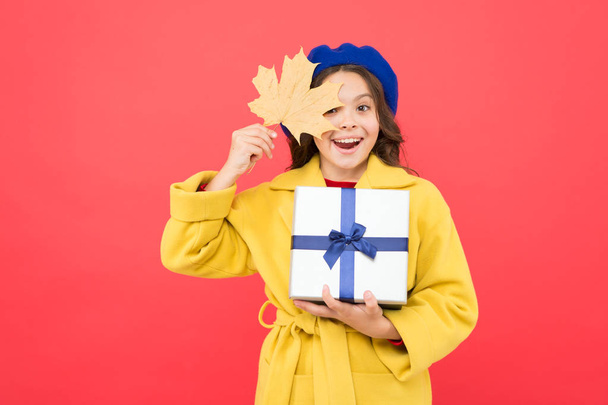 Child got present. Autumn shopping. Seasonal sale. Received with thanks. Gifts of autumn. Black friday. Small girl fall outfit red background. Little girl and gift box. Kid hold autumn maple leaf - 写真・画像