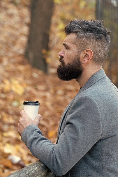 Man bearded hipster prefer coffee take away. Businessman bearded guy drink coffee outdoors. Hipster hold paper coffee cup and enjoy park environment. Relaxing coffee break. Drink it on the go - Zdjęcie, obraz