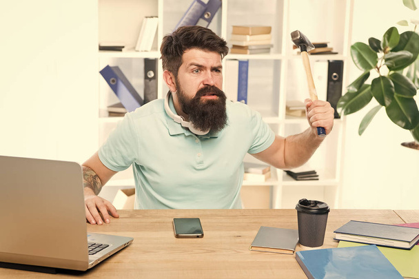Businessman with beard and mustache gone mad with hammer in a hand. Angry aggressive businessman in office. Frustrated office worker holding hammer poised ready to smash. Office life makes him crazy - Photo, Image