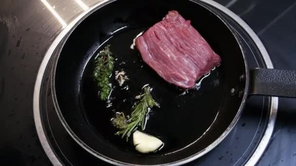 Velký steak se smažuje v pánvi v kuchyni v restauraci v těsné blízkosti - Záběry, video