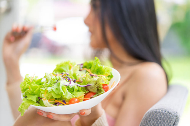 Woman is holding a big plate of salad eating at home - Photo, image