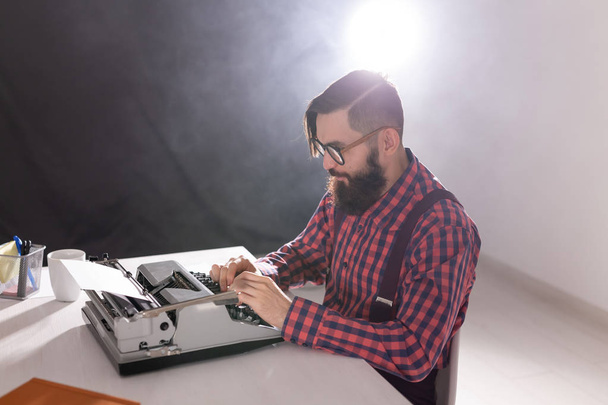 Concetto di persone e tecnologia - Vista laterale bell'uomo con la barba che lavora sulla macchina da scrivere su sfondo nero
 - Foto, immagini