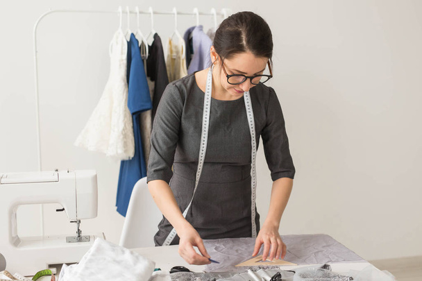 Μοδίστρα, σχεδιάστρια μόδας και ράφτης έννοια - όμορφη νεαρή στυλίστας στον εργασιακό χώρο κοντά σε rack με ρούχα - Φωτογραφία, εικόνα