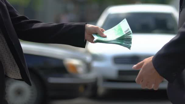 Kobieta dając euro do człowieka i drżenie rękę na tle samochodów, umowa najmu - Materiał filmowy, wideo
