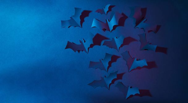 Halloween image of blue paper bats flying up on dark blue background. - Fotó, kép