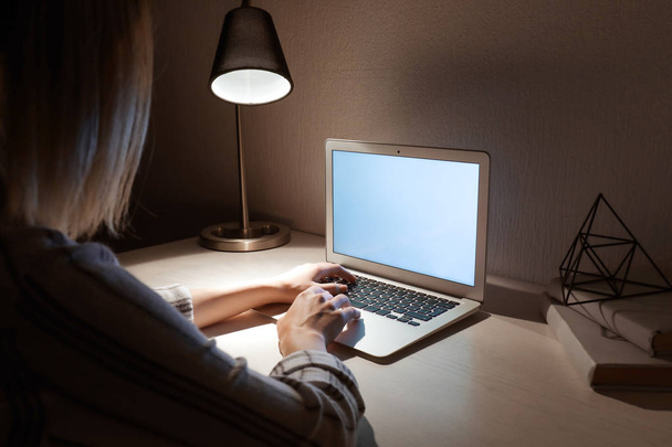 Жінка працює на ноутбуці за столом ввечері
 - Фото, зображення