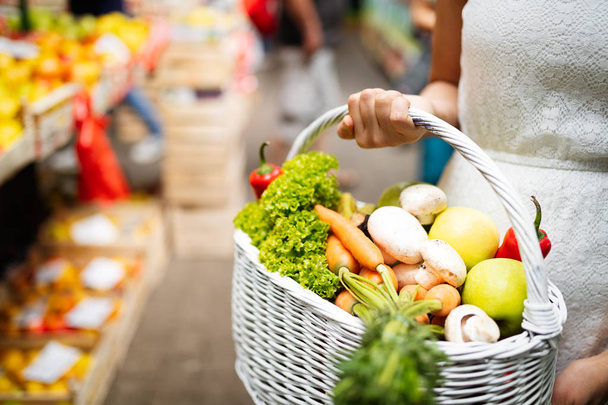 Woman holding a basket with healthy fresh organic vegetables - Фото, зображення