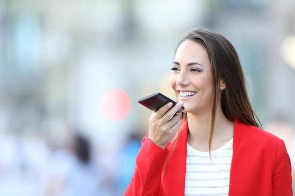 Happy woman in red using voice recognition on phone - Foto, afbeelding