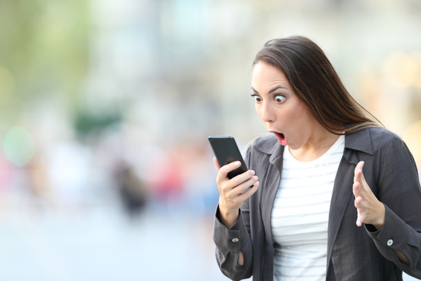 Amazed woman checking content on smart phone - Фото, изображение