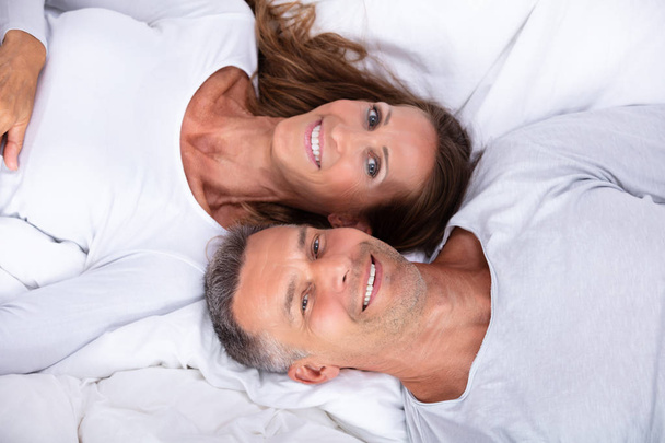 High Angle View Of Happy Mature Couple Lying On Bed - Фото, зображення