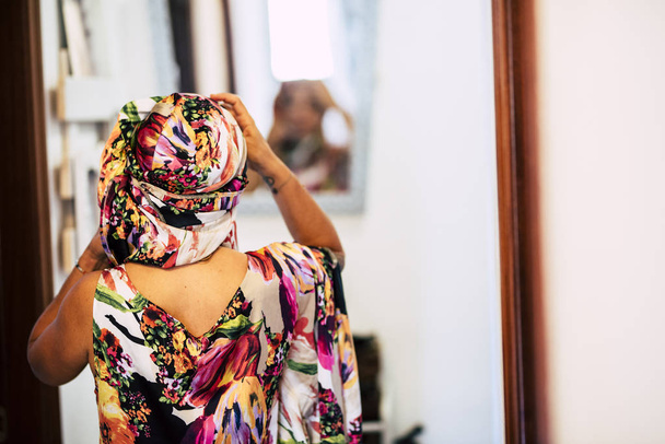Этническое разнообразие гонщица дома пробует цветное платье и фол перед зеркалом - Фото, изображение