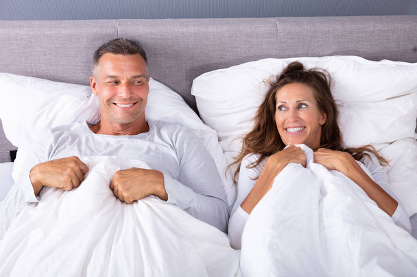 Happy Couple Lying On Bed With White Blanket In Bed Room - Foto, Imagen