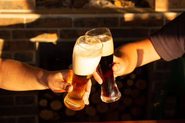 Due amici che brindano con bicchieri di birra chiara e scura al pub. Bellissimo sfondo dell'Oktoberfest
. - Foto, immagini