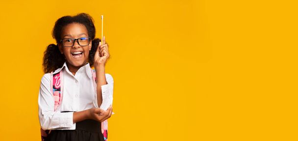Afro-amerikai Girl Raising kézi Holding ceruza, sárga háttér, panoráma - Fotó, kép
