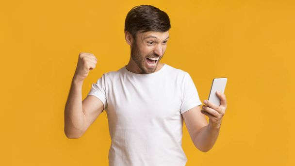 Щасливий чоловік тримає стільниковий телефон струшування кулаками святкування успіху, Панорама - Фото, зображення