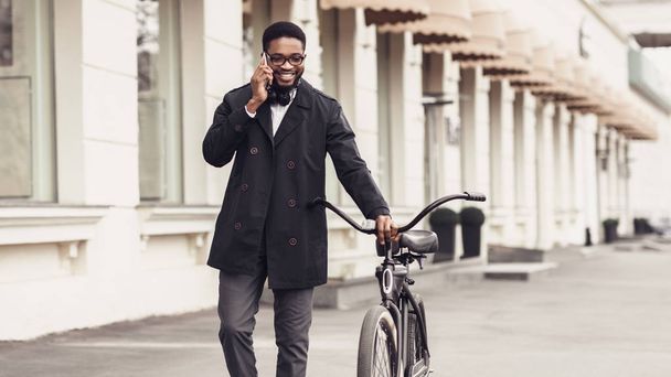 Уверенный бизнесмен ходит на велосипеде и разговаривает по мобильному телефону
 - Фото, изображение