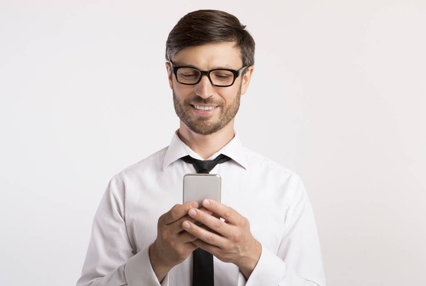 Sonriente hombre mensajes de texto en el teléfono celular sobre fondo blanco
 - Foto, Imagen