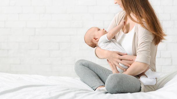 junge Mutter wiegt Neugeborenes in den Armen - Foto, Bild