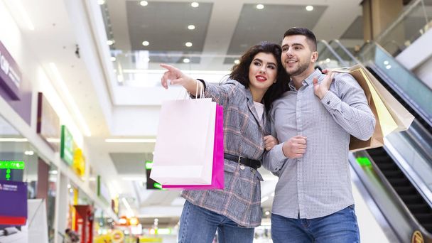 Concepto de ventas. Mujer mostrando hombre tienda en el centro comercial
 - Foto, imagen