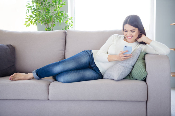Portrait of her she nice attractive charming lovely cheerful cheery woman lying on cosy divan using web services wi-fi in light white interior living-room indoors - Foto, afbeelding