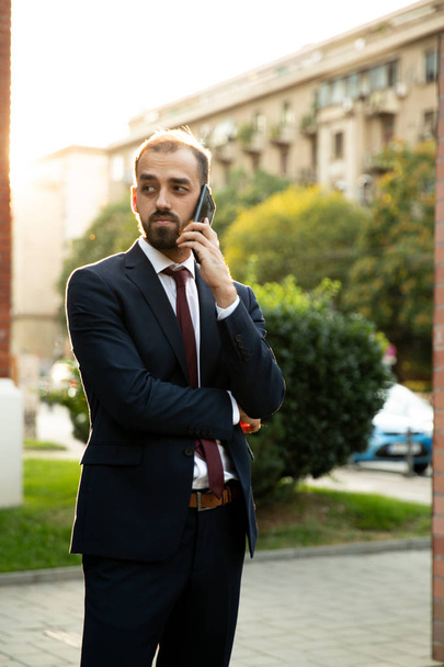 Succesvolle zakenman praten op de telefoon bij zonsondergang - Foto, afbeelding