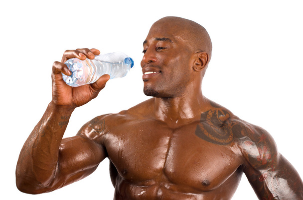 Black bodybuilder drinking water after a hard workout. Strong man with perfect muscles. Isolated on white background. - Foto, afbeelding
